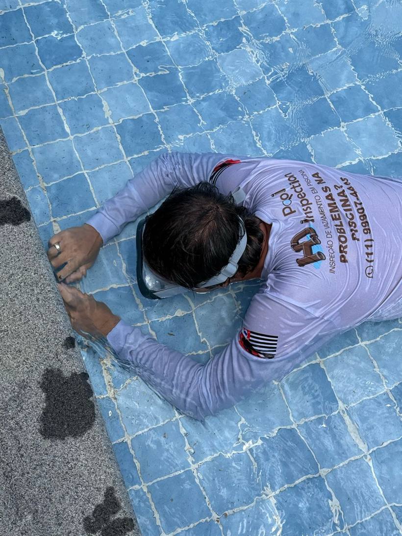 Técnico uniformizado da HD Pool Inspection com a máscara submersa examinando a parede da piscina